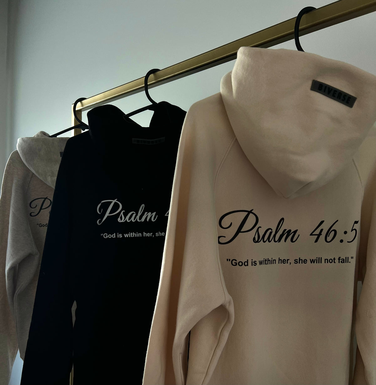 Beige, Black and Grey BIVERSE 23' hoodies hanging with printed text on the back.