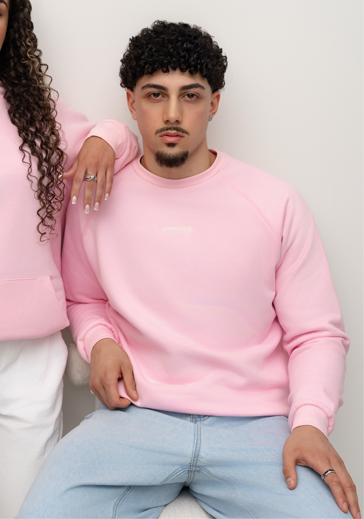 Seated model wearing the Candy pink BIVERSE crewneck, front view.