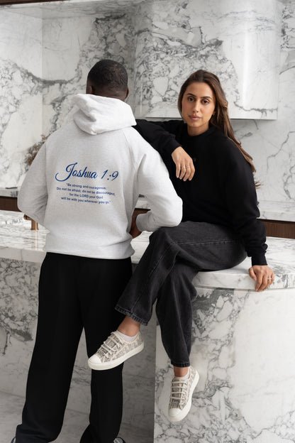 Snow white BIVERSE hoodie with a printed verse on the back beside a model in a Noir black crewneck.