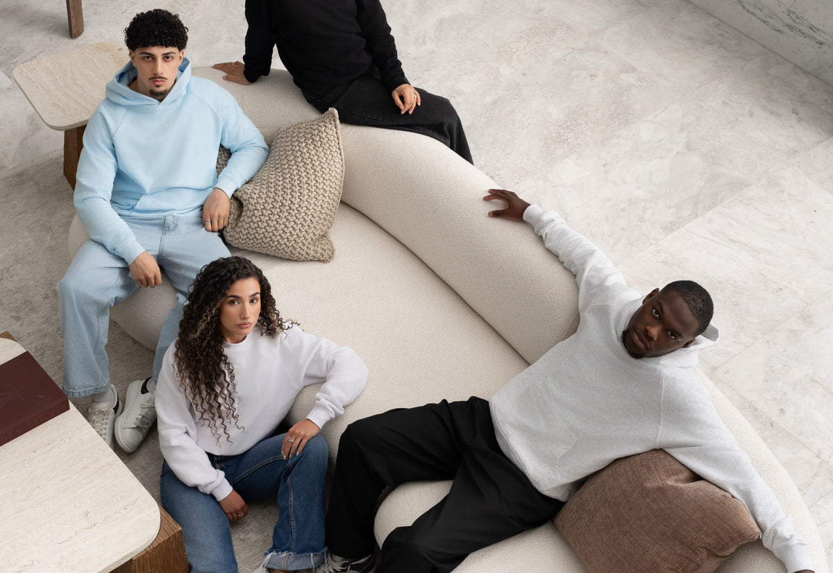 Group wearing BIVERSE blue, white and black pieces around a studio sofa.