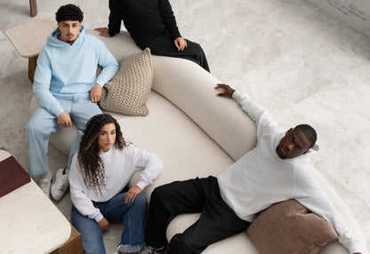 Group wearing BIVERSE blue, white and black pieces around a studio sofa.