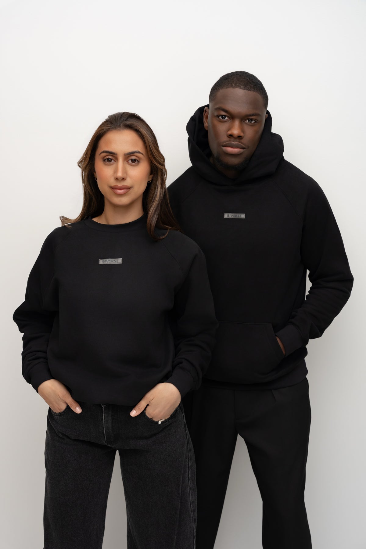 Models wearing the Noir black BIVERSE crewneck and hoodie, front view.